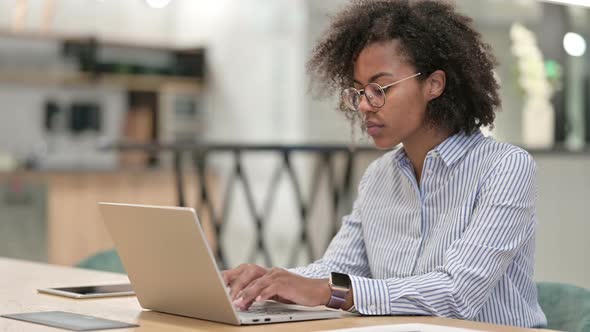 Young African Businesswoman with Laptop Smiling at Camera in Office