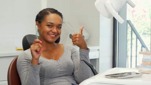 Attractive Woman with Perfect Smile Showing Thumbs Up and a Toothbrush