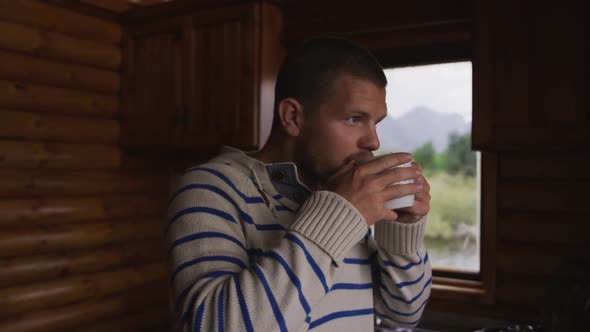 Caucasian man spending time at home, drinking a beverage, looking at the window