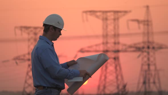 Electrician and High Voltage Electric Lines at Sunset