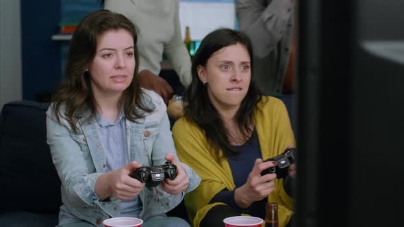 Front View of Womens Playing Videogames Battle on Television Using Gaming Controller