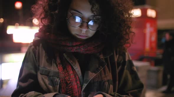 Young multi ethnic woman outdoor using smart phone at night