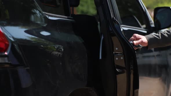 Male Hand Opens the Door of a Black Business Class Car. Silhouette of a Woman in an Elegant Dress