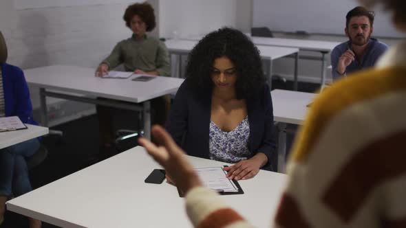 Mixed race colleuagues sitting during presentation in meeting room making notes