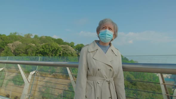 Senior Vaccinated Woman Putting Off Medical Mask Outdoors