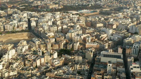 Beige Brown Apartment Blocks in Hot Area in Sunlight on Malta Island, Aerial Wide View Drone Slide