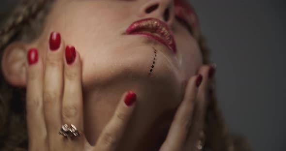 Sexy Model Wearing Red and Gold Makeup with Jewelry Posing in the Studio, 