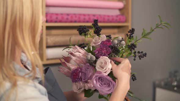 Side View of Female Blonde Florist Arranging Modern Bouquet and Looking How the Flowers are Combined