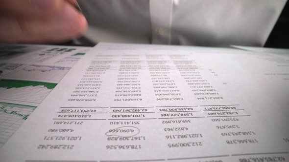 Accountant analyzing business marketing data on paper dashboard at office table.