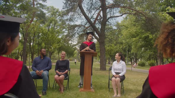 Joyful Male Arab Graduate Giving Talk to Fellow Students at Graduation Day