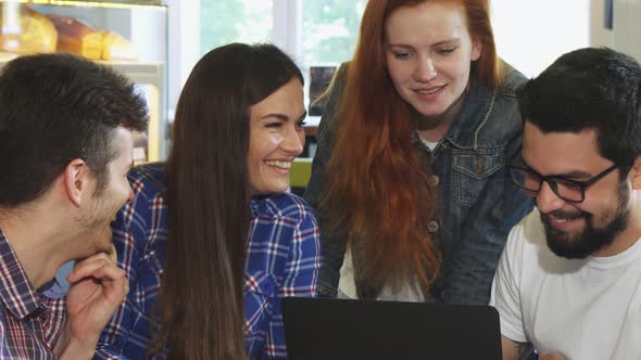 Group of Friends Laughing While Using Laptop Together