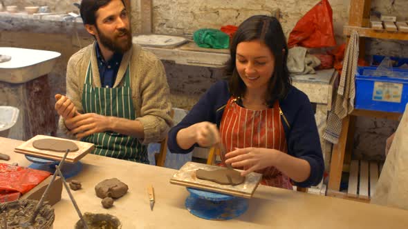 Male and female potters molding a clay