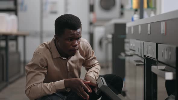 Male Shopper is Viewing Oven in Trading Area of Hardware Shop Viewing Inside Choosing Best Device