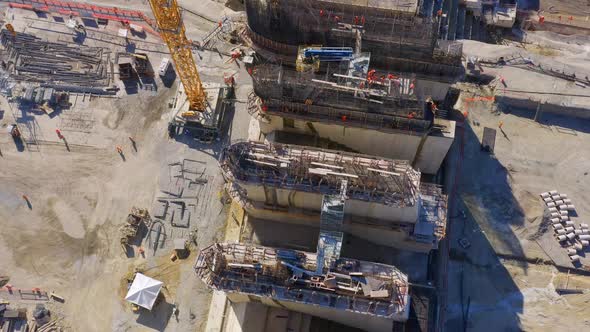 Top-down drone view of the Monte Grande dam building site with workers walking, Barahona, Dominican