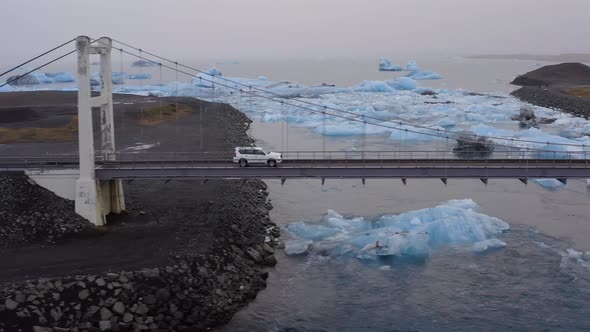 Car Driving on a Cable Bridge Above the Glacial River with Large Ice Splinters