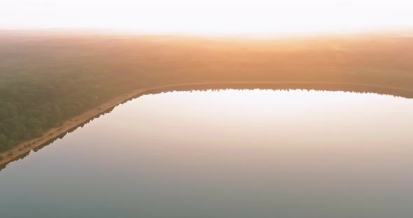 Morning Mist Blankets a Forest Lake in a Foggy Sunrise