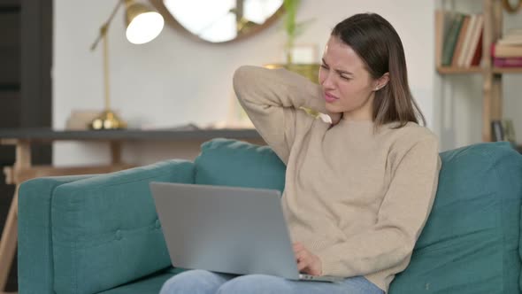 Laptop Work By Young Woman with Neck Pain on Sofa