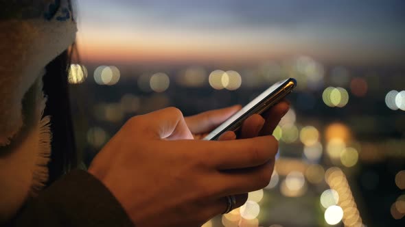 Beautiful Close-up on Female Hands Using Smartphone Shopping App at Amazing Bokeh Sunset City Lights