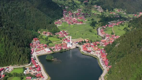 aerial drone of a lake surrounded by a small mountain village in Uzungol Trabzon on a sunny summer d