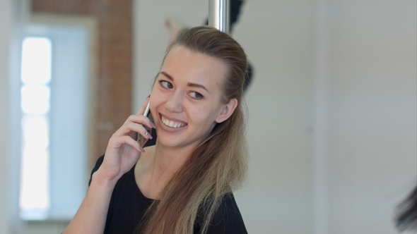 Happy Pole Dancer Calling with A Cell Phone During a Class