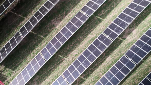 Flying diagonally over horizontal rows of photovoltaic solar panels, aerial top down