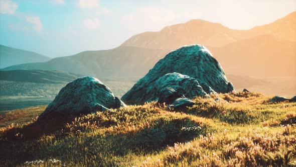 Meadow with Huge Stones Among the Grass on the Hillside at Sunset