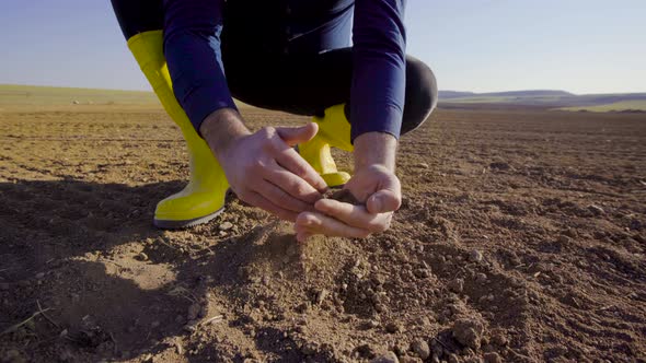 Grabs and pours the soil with the farmer's hand.