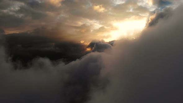 Aerial View Flying Through Cumulus Thunderclouds at Sunset. Gold Colored Sunset Cloudiness in High