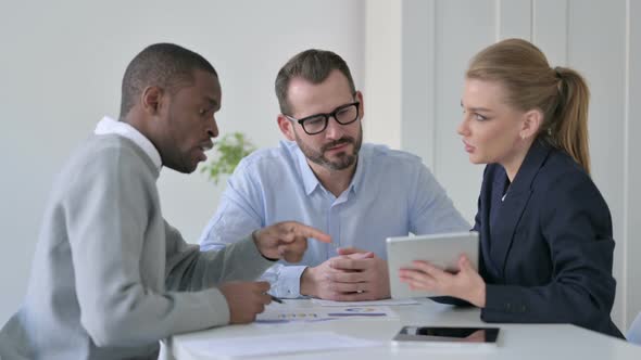 Male and Female Businessperson with Documents and Tablet Having Discussion