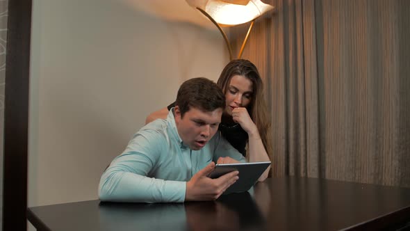 Married Couple Surfing on Digital Pad at Home