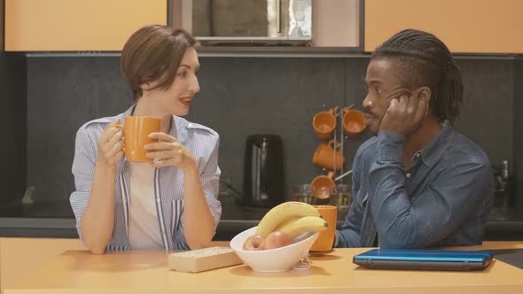 Young Caucasian Woman and African American Man Drinking Tea or Coffee From Orange Cups and Talking