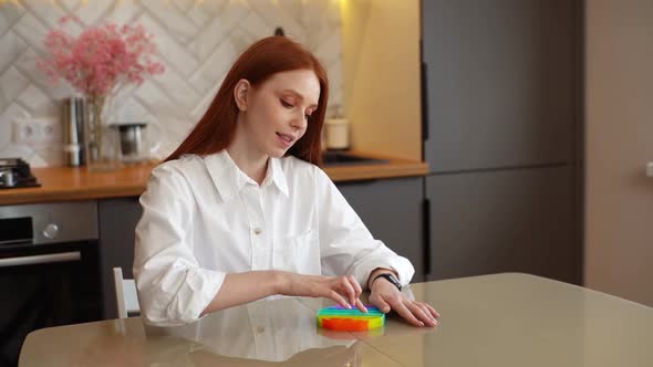 Happy Beautiful Young Woman Playing with Rainbow Popit Fidget Toy As Musical Instrument at Home