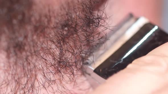 Close Up of a Young Man Shaving His Beard with an Electric Razor