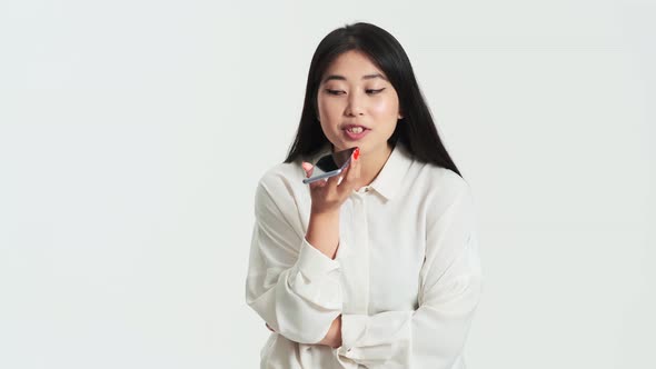 Beautiful asian korean woman recording voice message using her phone