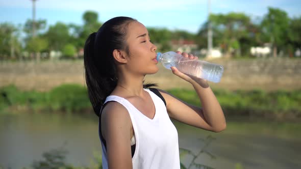 Young woman drinking water after exercise