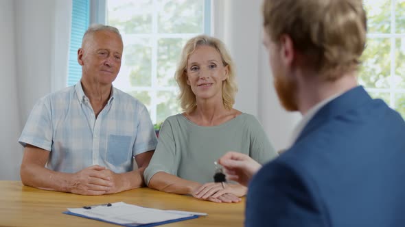 Sales Manager Giving Home Key To Mature Couple After Deal