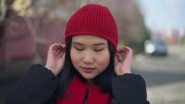 Portrait of Young Charming Confident Asian Woman Adjusting Red Hat Looking at Camera Smiling