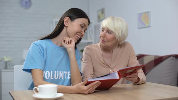 Mature Woman Showing Female Volunteer Photo Album, Nursing Home Leisure, Care