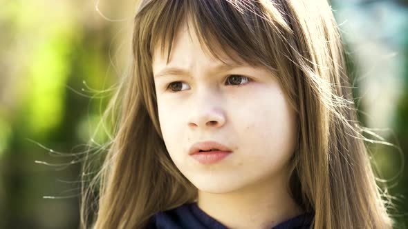 Portrait of Pretty Child Girl with Gray Eyes and Long Fair Hair Smiling Outdoors on Blurred Green