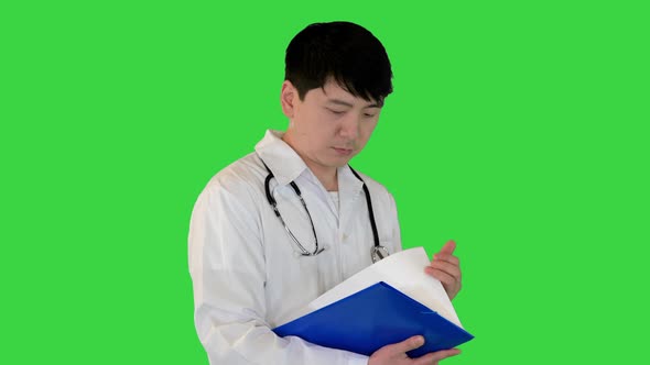 Young Asian Doctor Walks Studying a Document on a Green Screen Chroma Key