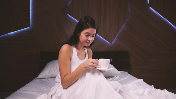 Attractive Young Girl at Home. Drinking Coffee in Her Bed