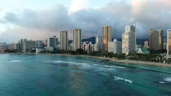 Panning shot of Waikiki beach on a tropical stormy day, waves rolling in while surfers wait. Honolul