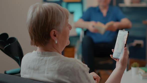 Senior Woman with Crutches Enjoying Online Video Call on Smartphone