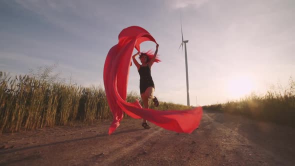 Woman with Pieces of Red Cloth Run to the Wind Generator in the Field