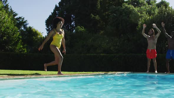 Diverse group of friends having fun jumping into a swimming pool