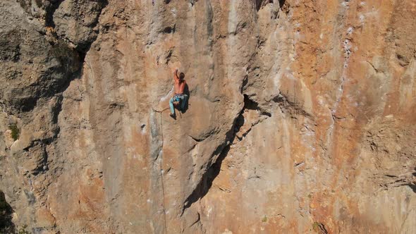 Aerial View From Drone of Strong Muscular Young Man Climbs on Big Rocky Wall By Challenging Rock