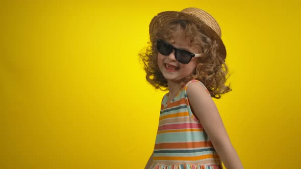 Cute Little Girl in Sunglasses with Toothless Smile is Dancing in Yellow Studio