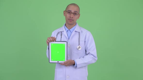 Stressed Bald Multi Ethnic Man Doctor Talking While Showing Digital Tablet