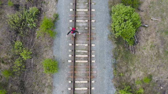 A Tourist with a Backpack Goes on the Rail of the Railway