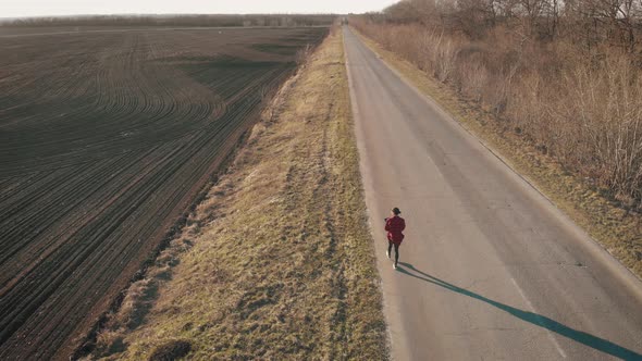 Aerial View of Woman Farmer with Digital Tablet Computer Looks at a Fresh Plowed Field After Winter